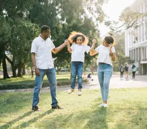 Two adults swinging a child in the air.